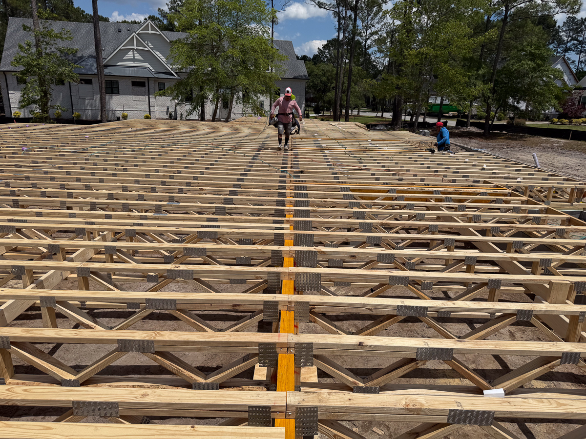Aerial view of engineered floor truss system with crew members walking the deck