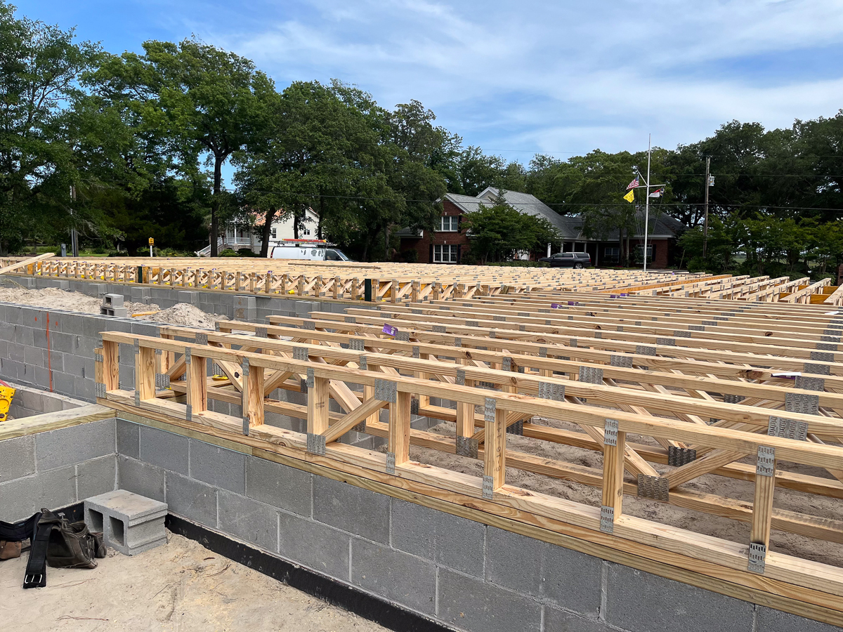 Close-up of engineered floor trusses set on a block foundation with coastal home in background