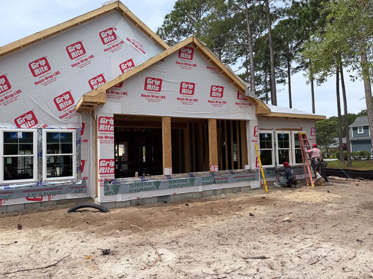 Coastal home wrapped in Grip Rite house wrap with covered front porch and crew installing windows